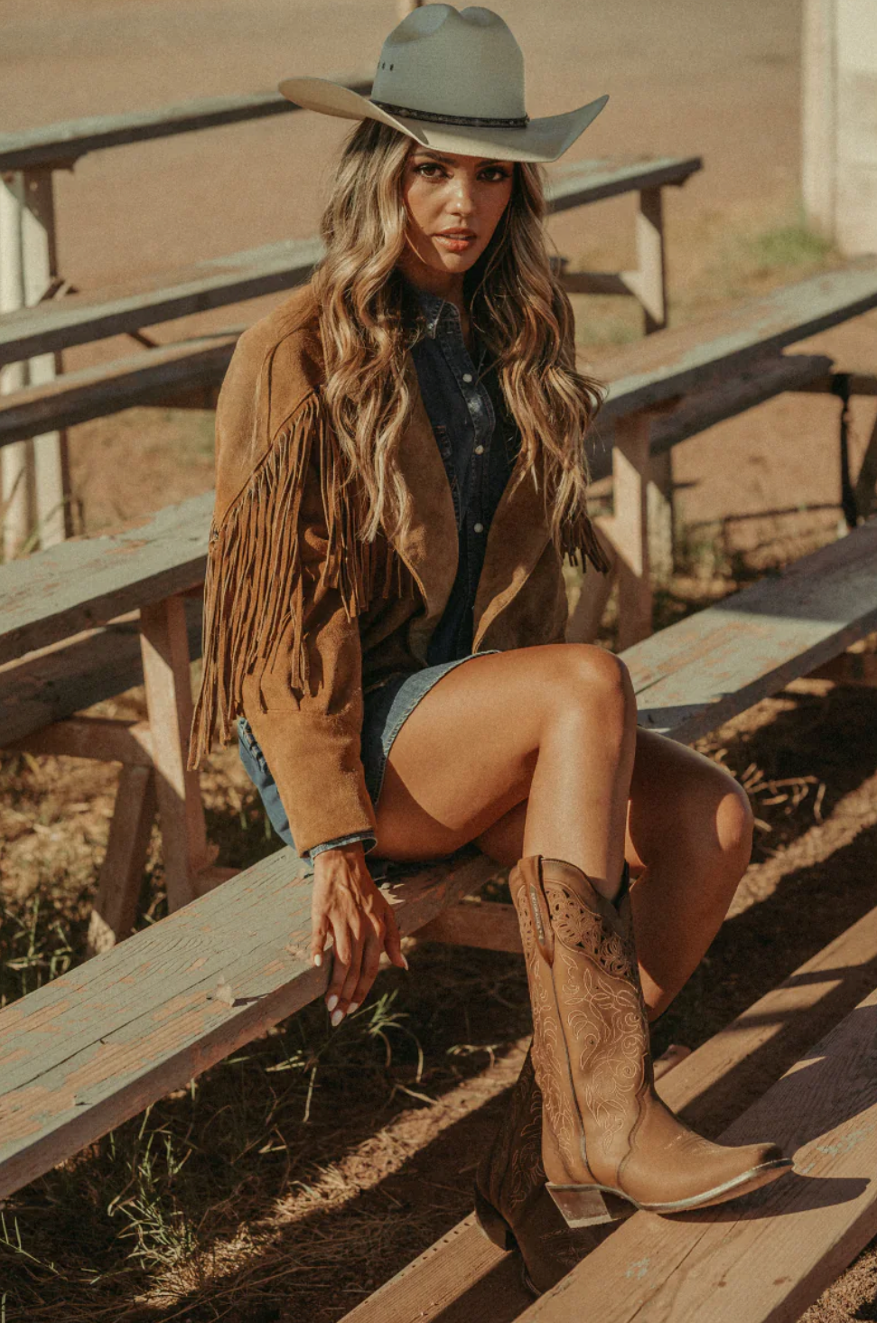 Modelo luciendo las Botas Vaqueras Alta Rio Grande Melissa en un estilo lifestyle vaquero, con sombrero, chaqueta de cuero y tejanas, demostrando la versatilidad y elegancia del estilo vaquero.