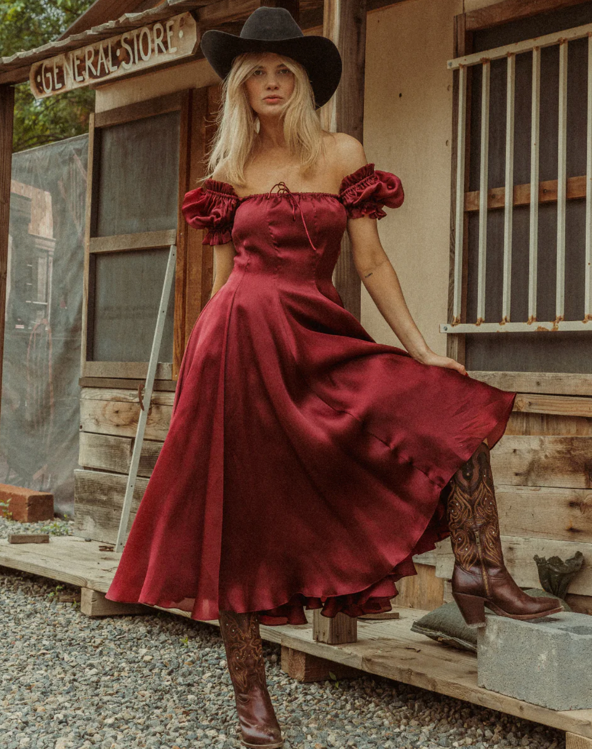 Modelo con vestido rojo y tejana, mostrando cómo lucen las botas con su outfit, combinando estilo western y elegancia, disponible en Boot Place.